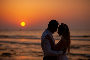 Bride and groom, newlyweds, honeymoon on the beach sunset sun