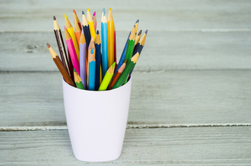 colored pencils in a glass on a wooden background