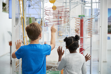 Two kids looking at a science exhibit,  back view - obrazy, fototapety, plakaty