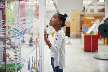 Young black girl looking at a science exhibit, close up - Powered by Adobe