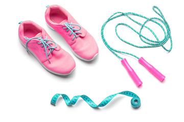 Jump rope, sneakers and measuring tape on white background