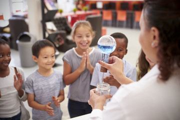 Lab technician showing excited kids an experiment, close up