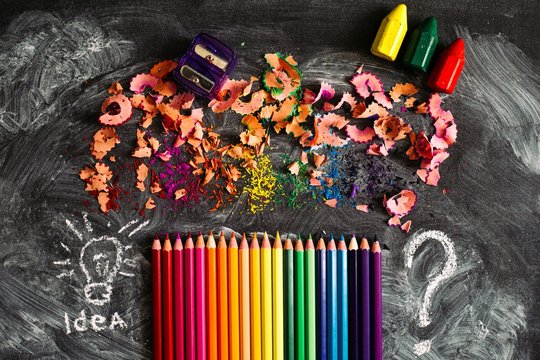 Sharpened pencils laid out on the school Board with colored sawdust