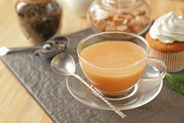 Cup of aromatic tea with milk on slate plate