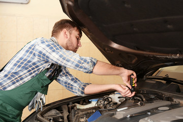 Fototapeta na wymiar Young auto mechanic repairing car in service center