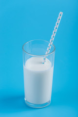 Glass of fresh milk with straw on a blue background. Concept of healthy dairy products with calcium
