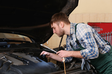 Young auto mechanic repairing car in service center