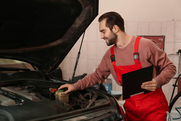 Young auto mechanic repairing car in service center