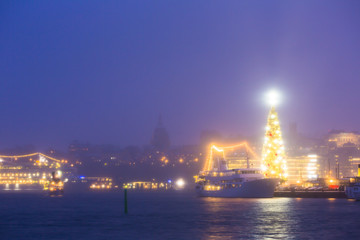 Fototapeta premium Beautiful winter scenery panorama of the Old Town (Gamla Stan) pier architecture with decorated gleaming Xmas Tree in Christmas and New Year holidays in Stockholm city, Night Sweden illuminated lights