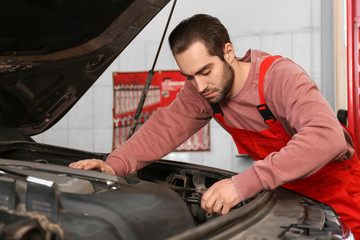 Fototapeta na wymiar Young auto mechanic repairing car in service center