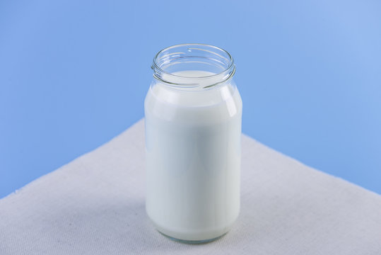 Glass bottle with fresh milk on blue background. Colorful minimalism. Healthy dairy products with calcium