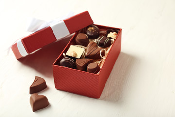 Box with tasty chocolate candies on wooden table