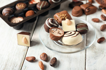 Plate with tasty chocolate candies on wooden table