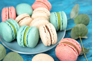 Plate with tasty macarons on table, closeup