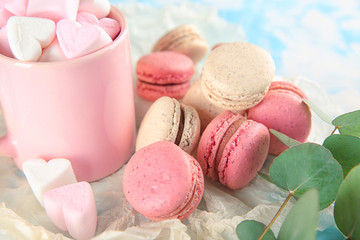 Tasty macarons and mug with marshmallows on table