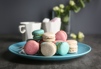 Plate with tasty macarons on table