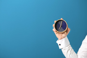 Man holding clock on color background. Time management concept