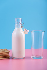Glass bottle of fresh milk and cookies on pastel background. Concept of healthy dairy products with calcium