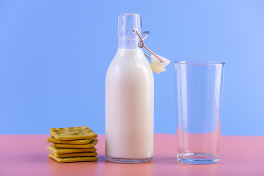 Glass bottle of fresh milk and cookies on pastel background. Concept of healthy dairy products with calcium