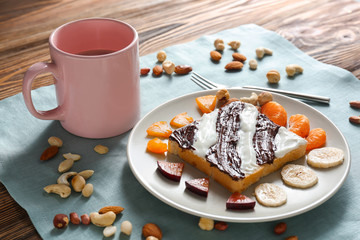 Plate with creative toast and cup of cocoa drink for children on table