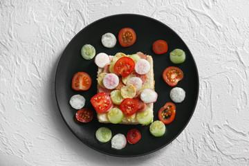 Plate with creative toast with vegetables for children on textured background