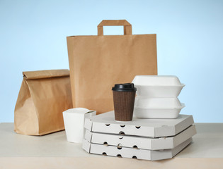 Different packages on table against color background. Food delivery service