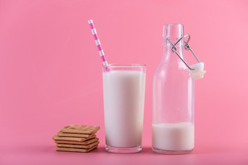 Glass bottle of fresh milk and cookies on pink background. Colorful minimalism. Healthy dairy products with calcium