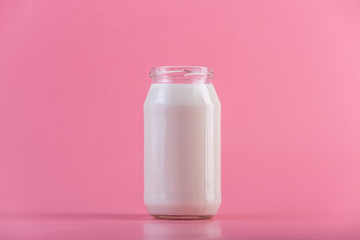 Glass bottle with fresh milk on pink background. Colorful minimalism. Healthy dairy products with calcium