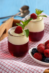 Pannacotta with berry jelly and berries on wooden tray. 