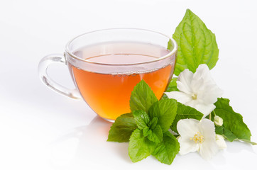 Glass cup of Tea with jasmine flowers and leaves of mint