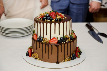 Wedding cake with chocolate and berries on table with white tablecloth