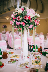 Table setting at a luxury wedding reception. Wedding decorations with flowers. Newlyweds party decor in restaurant reception.  Place for text.