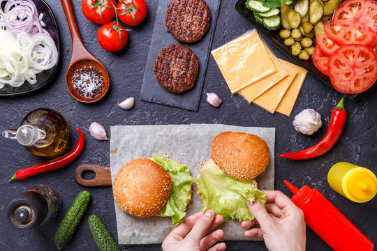 Photo on top of two hamburgers, human hands and ingredients