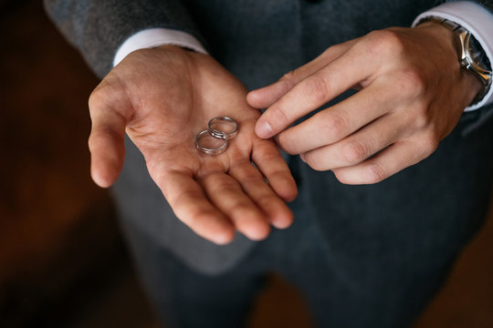 Groom holds on his palm two wedding rings