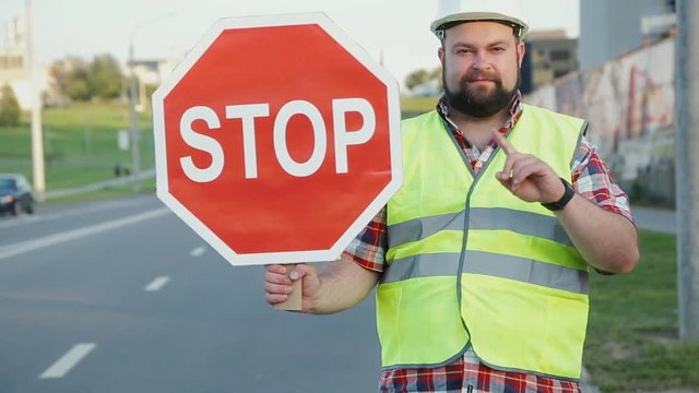 A construction road worker stopping traffic, holding a stop sign.
