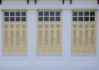 The wooden yellow windows on white wall in Thailand.