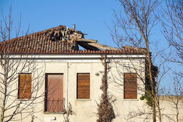 Broken brick bags on the roof of a cottage. Damaged roof.