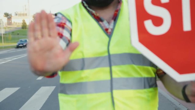 A construction road worker stopping traffic, holding a stop sign.