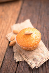 Close up a cup of almond cake against sack fabric on wooden table