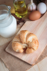Croissant on wooden cut board on table wood and fabric select focus shallow depth of field
