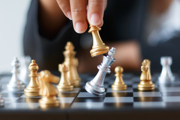 Close up shot hand of business woman moving golden chess to defeat and kill silver king chess on white and black chess board for business challenge competition winner and loser concept
