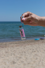 hand holding a bottle with desire on the background of a beautiful sea