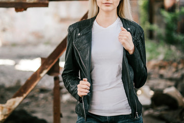 Girl wearing t-shirt and leather jacket posing against street , urban clothing style. Street photography
