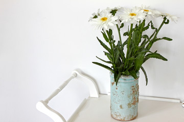 Still life with vase with chamomile flowers. Daisy flowers bouquet in clay vase on white wooden shabby table. Flower background. Floral pattern. Horizontal