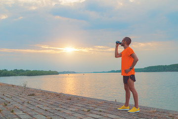 Tired jogger making a pause and drinking water.