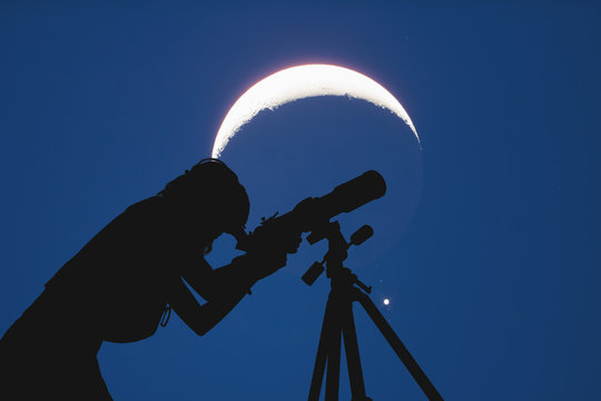 Silhouette of a girl beside astronomy telescope with Moon and Milky Way stars. 