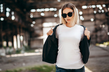 Girl wearing t-shirt and leather jacket posing against street , urban clothing style. Street...