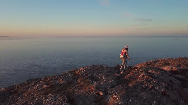 aerial view of woman hiker with a backpack hiking on the cliff above the sea and Bray cityscape in Ireland