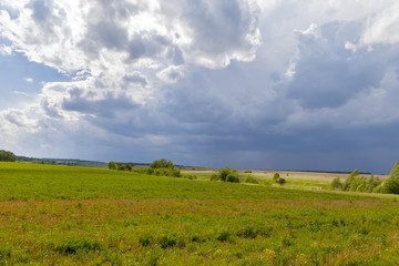 Green field and blue sky. Beautiful view of the grass and the hills on a sunny summer day.