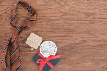 top view of tie with gifts and Happy fathers day greeting on wooden surface